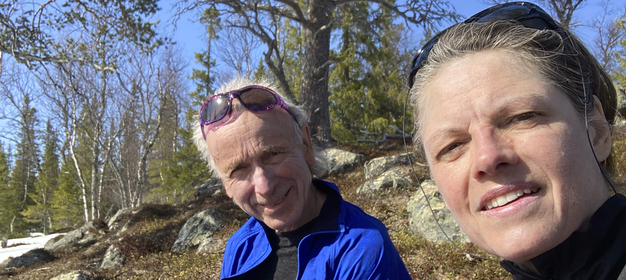 Karin och Mats sitter i en skogsbacke på vårvintern.
