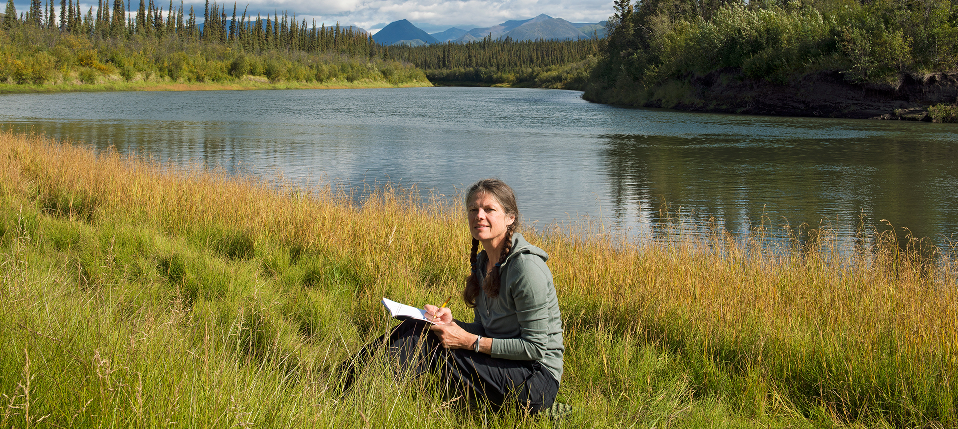 Karin sitter och skriver dagbok vid Bell River i norra Yukon, Kanada.