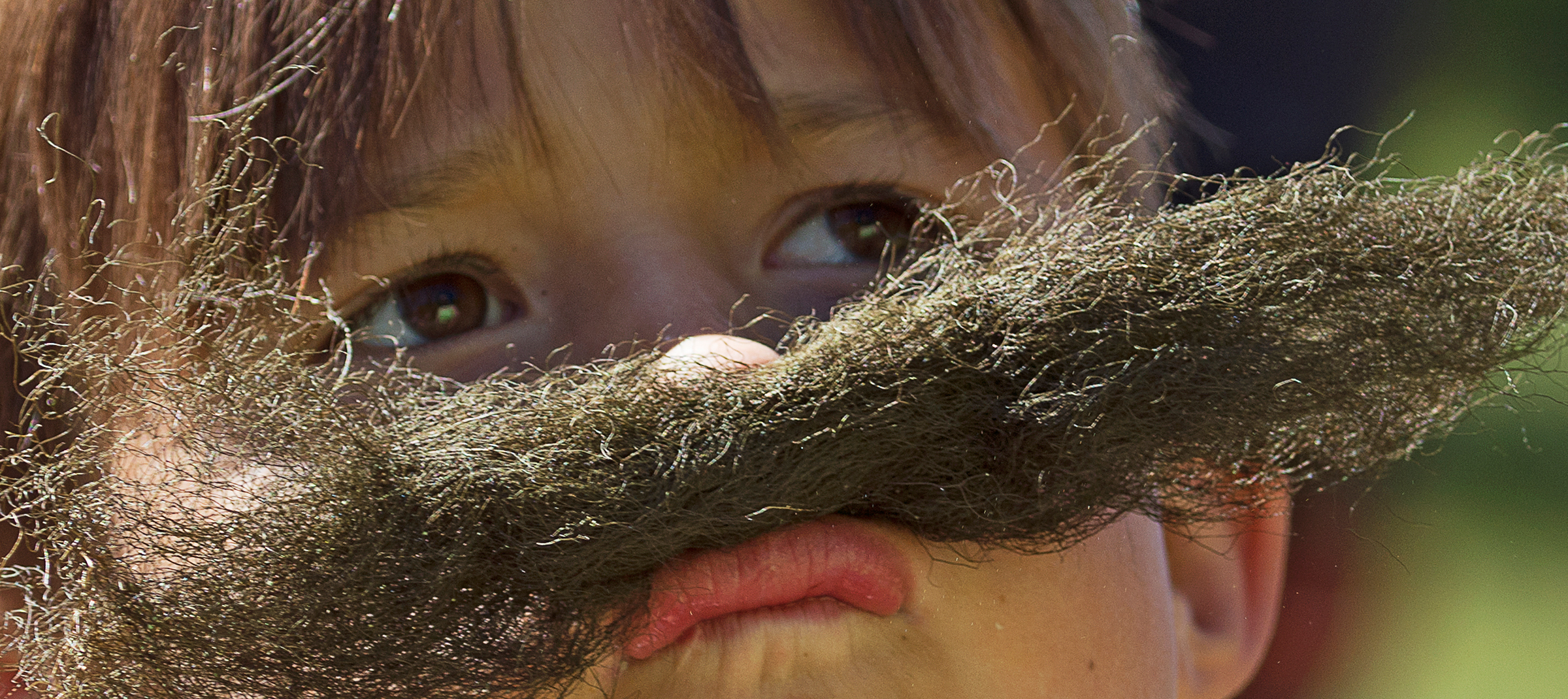 Barn som provar mustasch av hänglav.