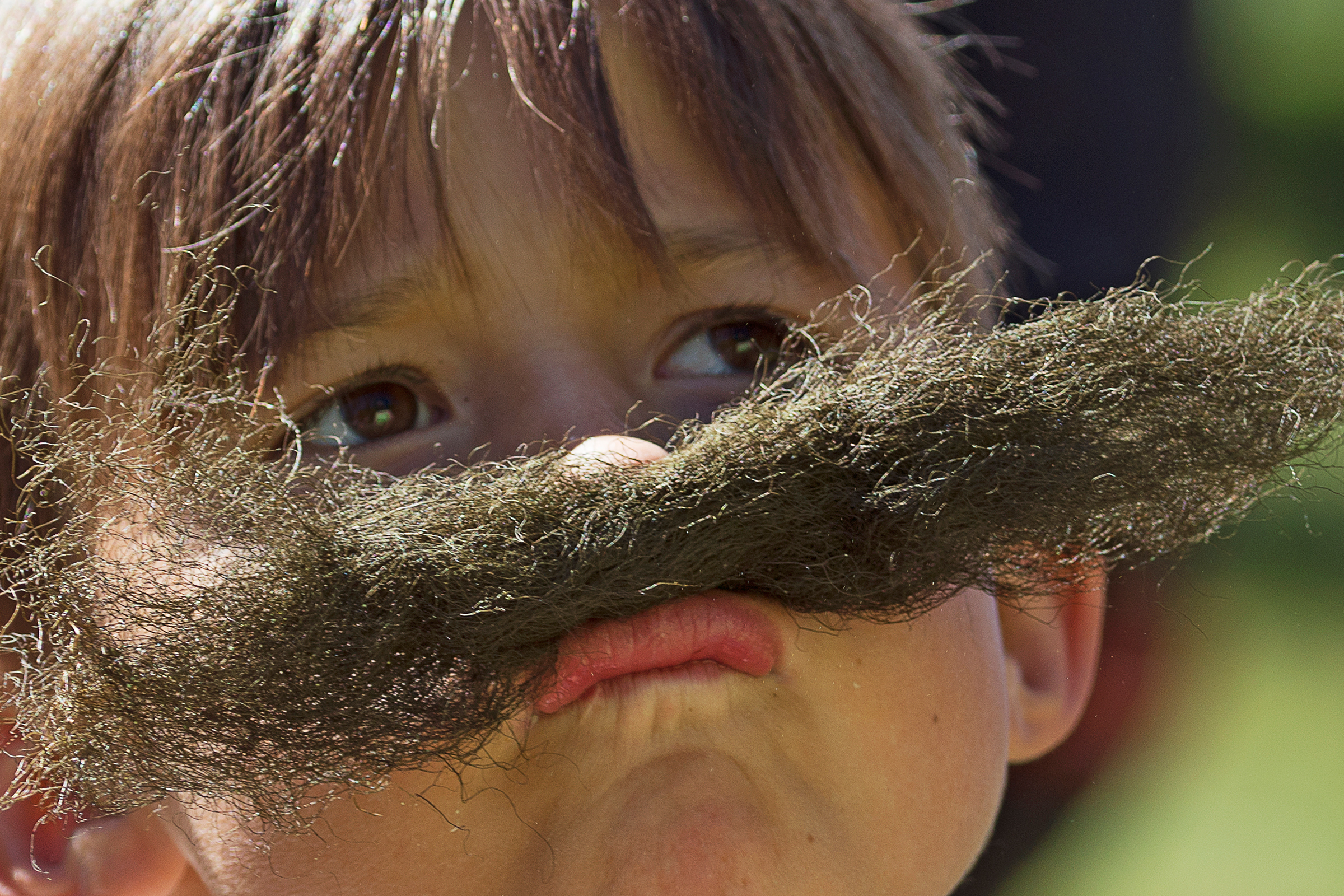 Barn som provar mustasch av hänglav.