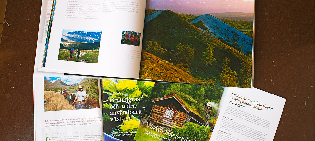 Uppslagen bok med naturbilder, olika broschyrer, samt ett uppslaget magasin med ett reportage.